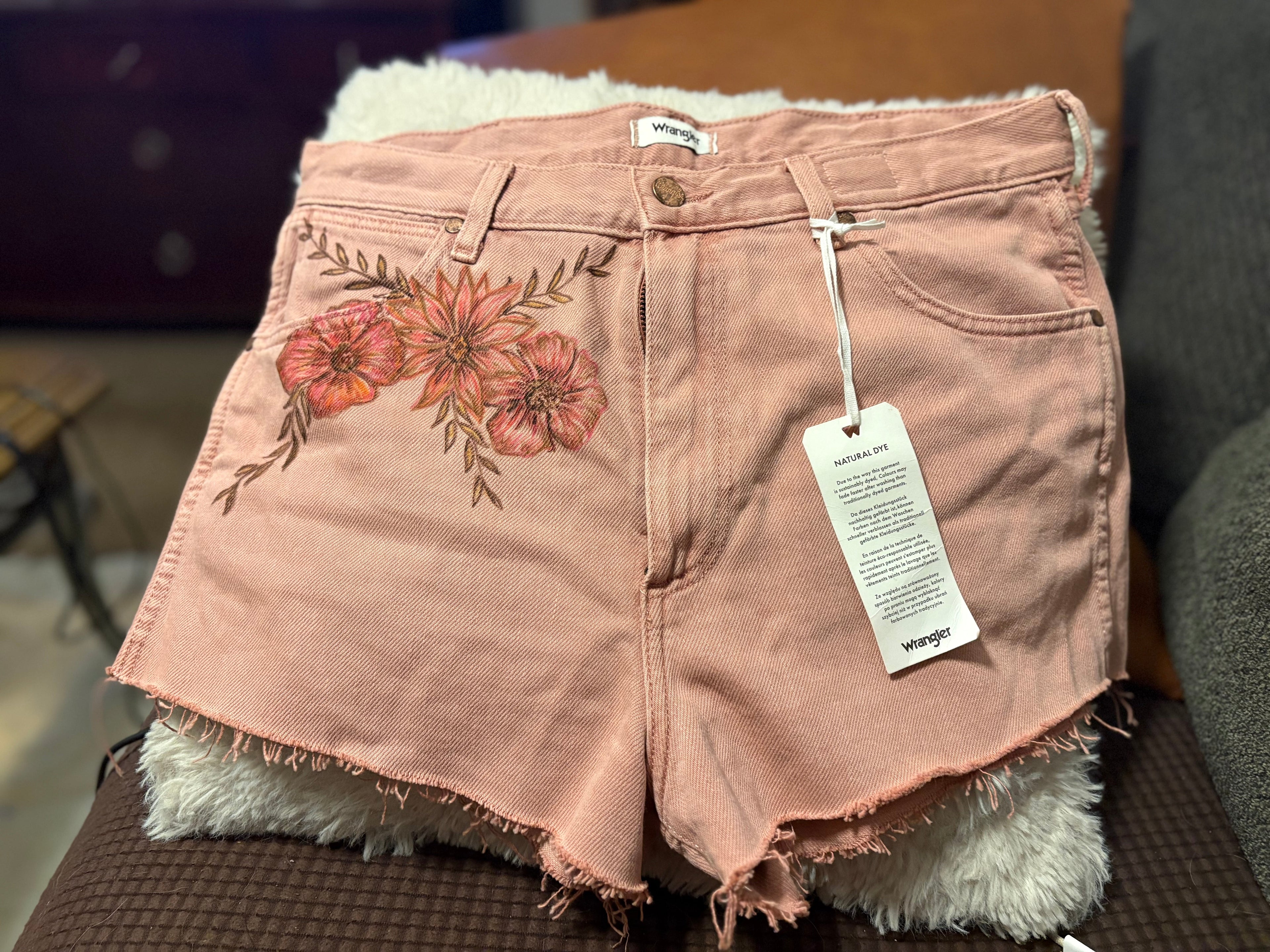 Front view of Wrangler dusty rose denim shorts with floral fabric paint detail